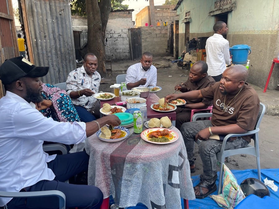 Personnes en train de manger autour d'une table dans un espace extérieur de quartier