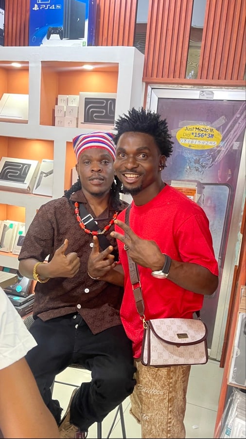 Two men posing together inside a modern retail shop with display shelves